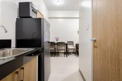 a kitchen with a stainless steel refrigerator and a dining room at Near SM BF & Shopwise SLEX Accessible 2BR for 4 in Manila