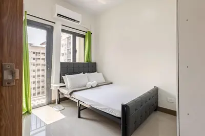 a bed in a room with a window at Near SM BF & Shopwise SLEX Accessible 2BR for 4 in Manila