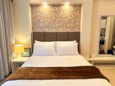 a bedroom with a large bed with a large headboard at COZY COVE IN venice MCKINLEY HILL in Manila