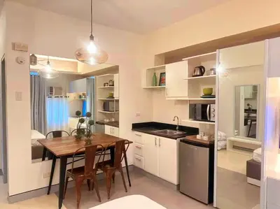 a kitchen with a table and a dining room at COZY COVE IN venice MCKINLEY HILL in Manila