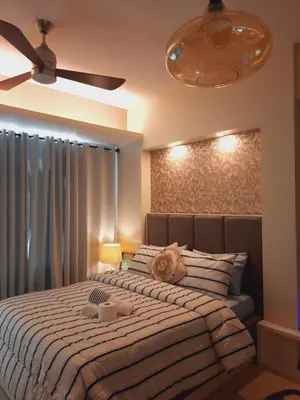 a bedroom with a large bed and a ceiling fan at COZY COVE IN venice MCKINLEY HILL in Manila