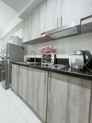 a kitchen with wooden cabinets and a counter top at Queen Bed with Coffee Bar and Fast Wi-Fi at S Residences in Manila