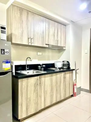 a kitchen with wooden cabinets and a sink at Queen Bed with Coffee Bar and Fast Wi-Fi at S Residences in Manila