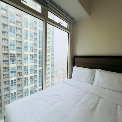 a bedroom with a white bed and a large window at Luxe 1BR BGC with Balcony in Manila