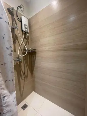 a shower in a bathroom with a wooden wall at Condotels by Tribecca Private in Manila