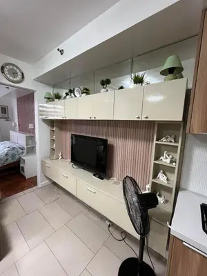 a living room with a desk with a tv and a chair at Antel Spa Residences 2509 in Manila