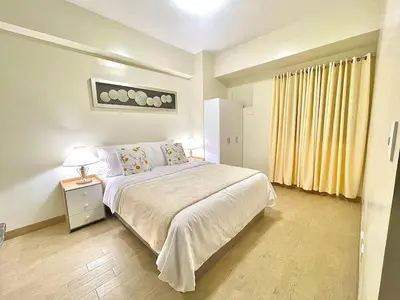 a bedroom with a bed and a night stand with a lamp at Manhattan Plaza Suite 1BR with City View, Netflix and Pool Access in Manila