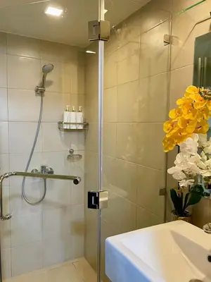 a bathroom with a shower and a sink and yellow flowers at Manhattan Plaza Suite 1BR with City View, Netflix and Pool Access in Manila