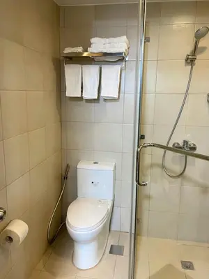 a bathroom with a toilet and a shower with towels at Manhattan Plaza Suite 1BR with City View, Netflix and Pool Access in Manila