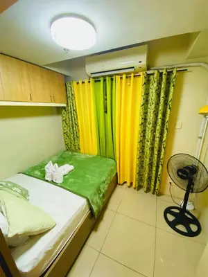 a small room with a bed with yellow and green curtains at 232 1br big balcony 2 queen size 1-sofa bed 1single extra mattress in Manila