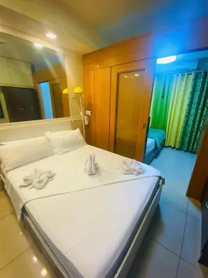 a bedroom with a white bed with towels on it at 232 1br big balcony 2 queen size 1-sofa bed 1single extra mattress in Manila