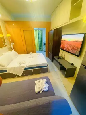 a hotel room with a bed and a sink at 232 1br big balcony 2 queen size 1-sofa bed 1single extra mattress in Manila