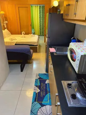 a small room with two beds and a kitchen at 232 1br big balcony 2 queen size 1-sofa bed 1single extra mattress in Manila