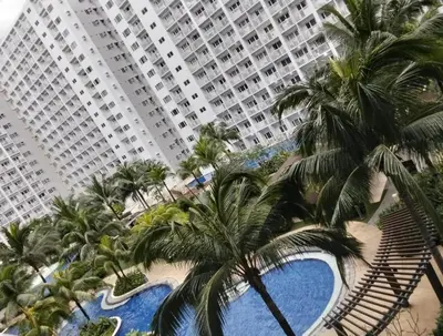 a large building with palm trees and a swimming pool at Urban Haven at Shore Residences Near MOA in Manila