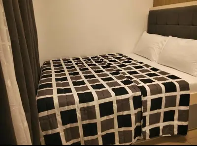 a bed with a black and white checkered blanket at Urban Haven at Shore Residences Near MOA in Manila