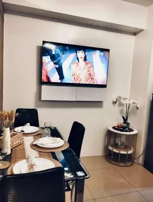 a dining room with a table and a tv on the wall at Urban Haven at Shore Residences Near MOA in Manila
