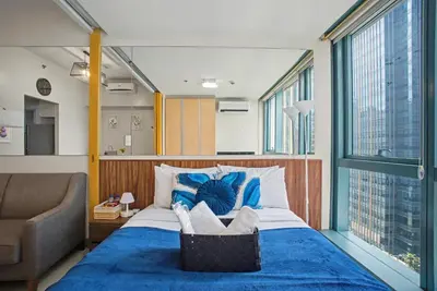 a bedroom with a large bed with a blue blanket at BGC High Rise, Uptown Mall Link, 5G WiFi, Pool, Ste 19 in Manila