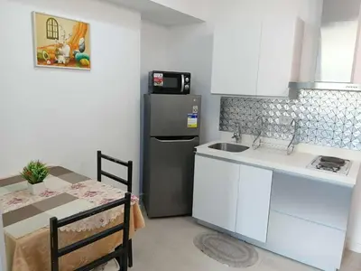 a small kitchen with a refrigerator and a table with a tableablish at Azure Residences 1 Bedroom with Wide Balcony in Manila