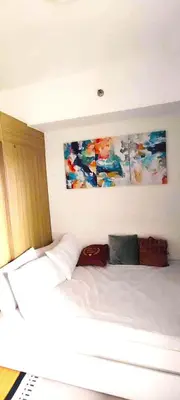 a bedroom with a white bed with a painting on the wall at Move In Condo in Taguig Fully Furnished in Manila
