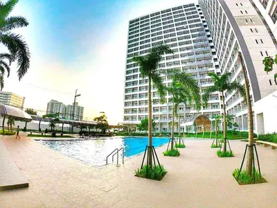 a large building with palm trees in front of a pool at Move In Condo in Taguig Fully Furnished in Manila