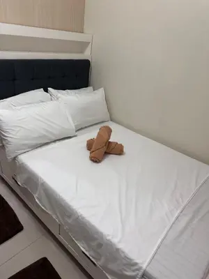 a brown teddy bear sitting on top of a bed at Sea Residences - Casa Juana at Mall of Asia in Manila
