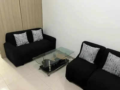 a living room with a black couch and a glass table at Sea Residences - Casa Juana at Mall of Asia in Manila