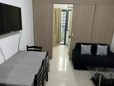 a room with a bed and a couch and a flat screen tv at Sea Residences - Casa Juana at Mall of Asia in Manila