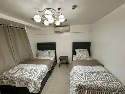 two beds in a room with a ceiling at Shell Residence 2 bedroom by Kathy in Manila