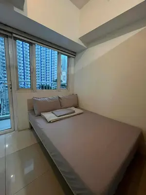 a room with a bed with a book on it at 1 BR Boni LIGHT Condo WIFI Netflix Pool Balcony in Manila