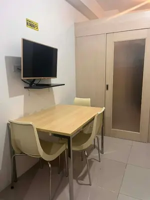 a wooden table with chairs and a television on a wall at 1 BR Boni LIGHT Condo WIFI Netflix Pool Balcony in Manila