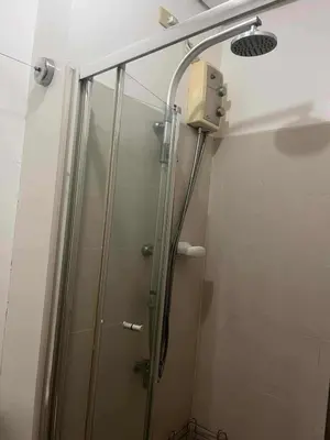 a shower with a glass door in a bathroom at 1 BR Boni LIGHT Condo WIFI Netflix Pool Balcony in Manila