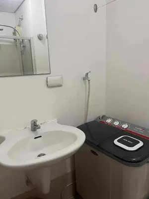 a bathroom with a white sink and a mirror at 1 BR Boni LIGHT Condo WIFI Netflix Pool Balcony in Manila