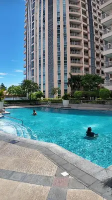 two people swimming in a large swimming pool with tall buildings at La Venezia Executive Home, 3 Bedroom, 7 adults Maximum plus Kids in Manila