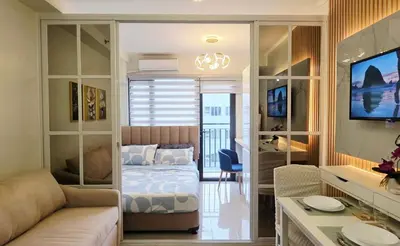 a bedroom with a bed and a living room at Executive Saver Suite 1BR Mall of Asia Airport in Manila