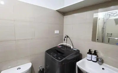 a bathroom with a toilet and a sink and a suitcase at Executive Saver Suite 1BR Mall of Asia Airport in Manila