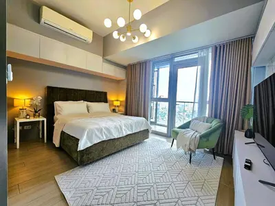 a bedroom with a bed and a chair and a window at Uptown BGC Residences by ChiKat in Manila
