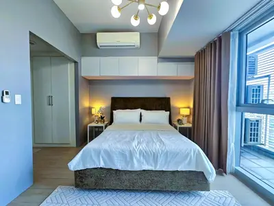 a bedroom with a large bed and a large window at Uptown BGC Residences by ChiKat in Manila
