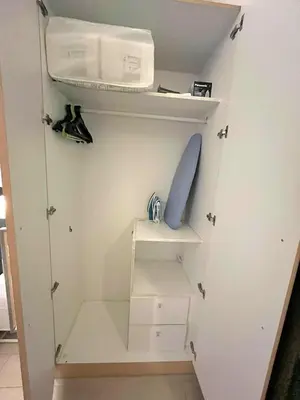 a small closet with white cabinets and a shelf at Uptown BGC Residences by ChiKat in Manila