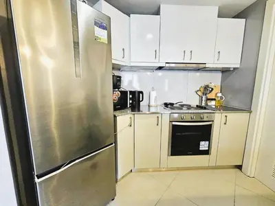 a kitchen with white cabinets and a stainless steel refrigerator at Uptown BGC Residences by ChiKat in Manila
