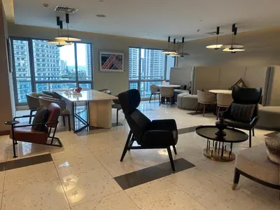 a lobby with chairs and tables in a building at Cleo Suites at Novotel Hotel Residences near Makati in Manila