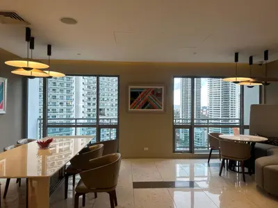 a living room with tables and chairs and large windows at Cleo Suites at Novotel Hotel Residences near Makati in Manila