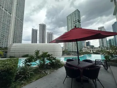 a patio with a red umbrella and chairs next to a pool at Cleo Suites at Novotel Hotel Residences near Makati in Manila