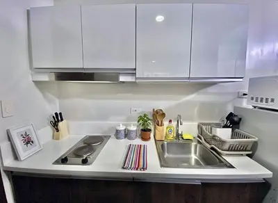 a kitchen with white cabinets and a sink at Air Residences 28F Balcony WiFi Netflix in Manila