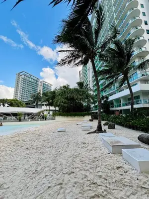 a sandy beach with a palm tree and buildings at Condotels SMB West Road in Manila