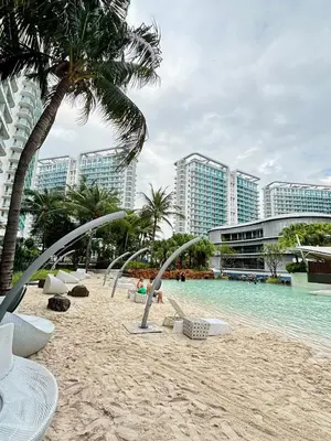 a beach with chairs and palm trees and buildings at Condotels SMB West Road in Manila