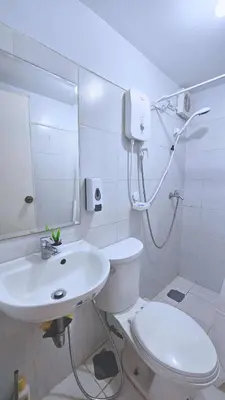 a white bathroom with a toilet and a sink at Bright & Airy Loft Cambridge Village Charm in Cainta