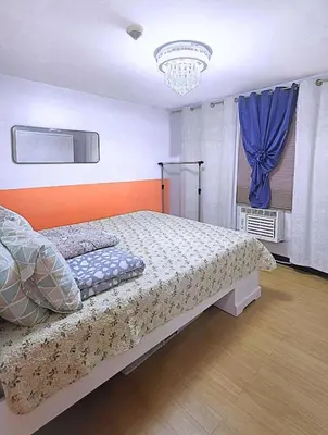 a bedroom with a bed and a blue curtain at Bright & Airy Loft Cambridge Village Charm in Cainta