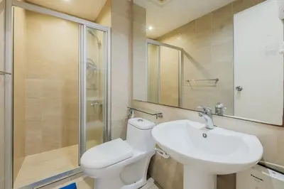a bathroom with a toilet and a sink and a shower at Free Parking at Gramercy with Big TV and Fast WiFi in Manila
