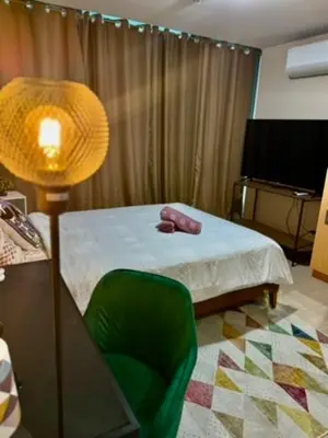 a bedroom with a bed and a lamp and a green chair at One Uptown Residences, BGC, Taguig in Manila