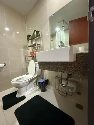 a bathroom with a toilet and a sink and a mirror at One Uptown Residences, BGC, Taguig in Manila